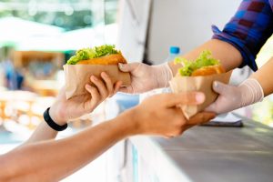Close-up of male hands buying two hot dog in a food truck